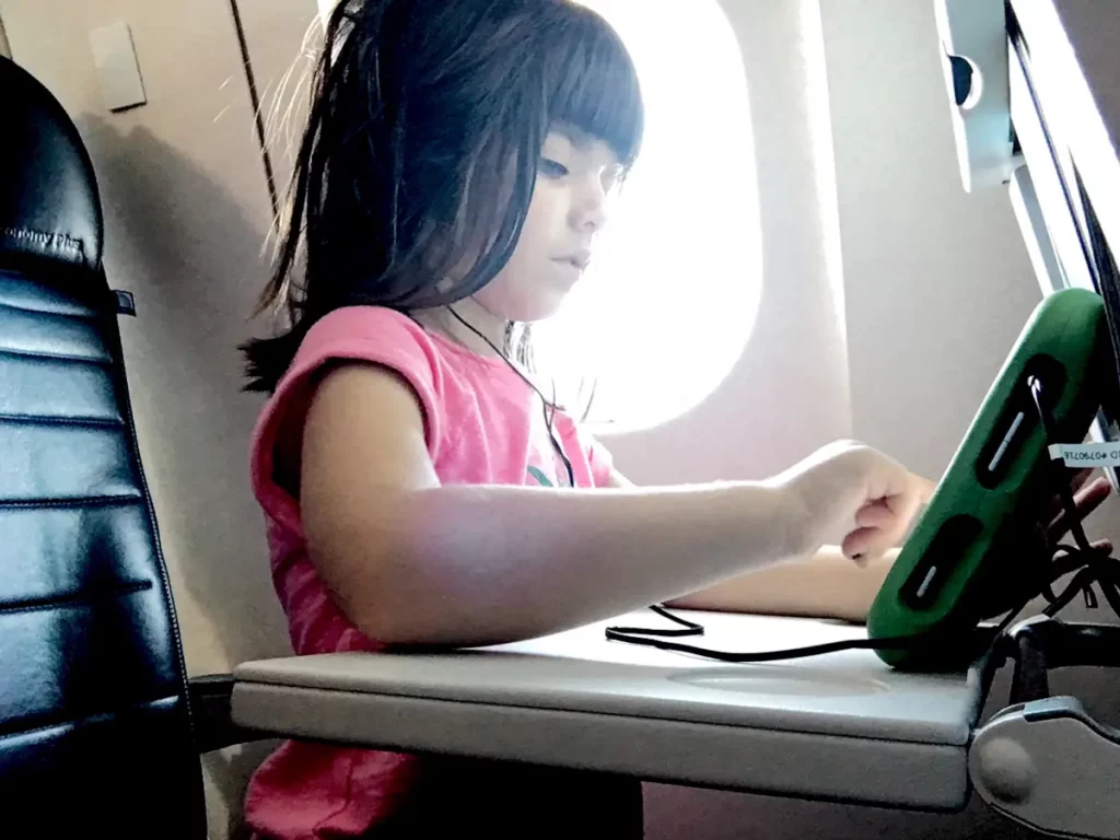 Kleines Mädchen im Flugzeug mit einem Tablet