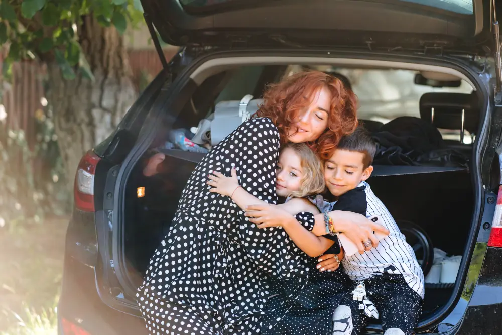 glückliche Frau mit zwei Kindern im Auto bei einer Pause