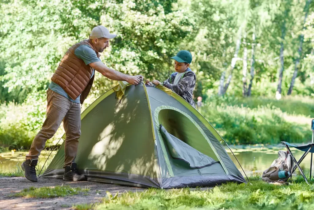 Vater und Sohn stellen ein Zelt auf am Campingplatz