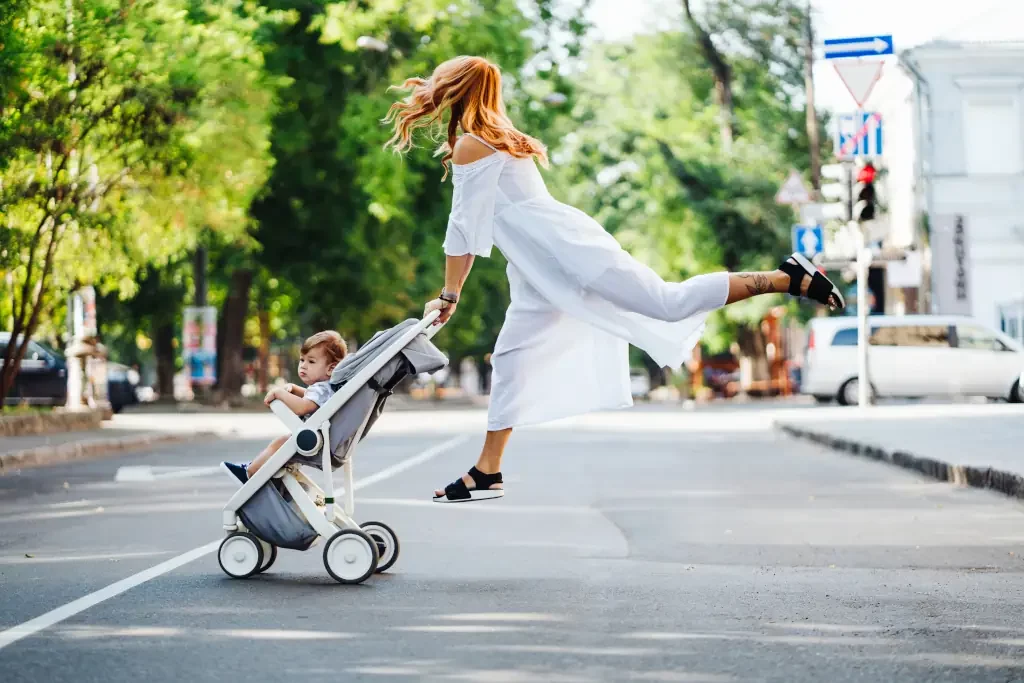 Mama mit einem Kinderwagen kreuzt die Straße