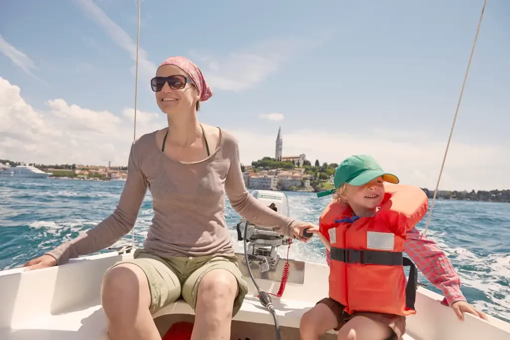 Frau mit Sohn steuert Motorboot, Rovinj, Halbinsel Istrien, Kroatien