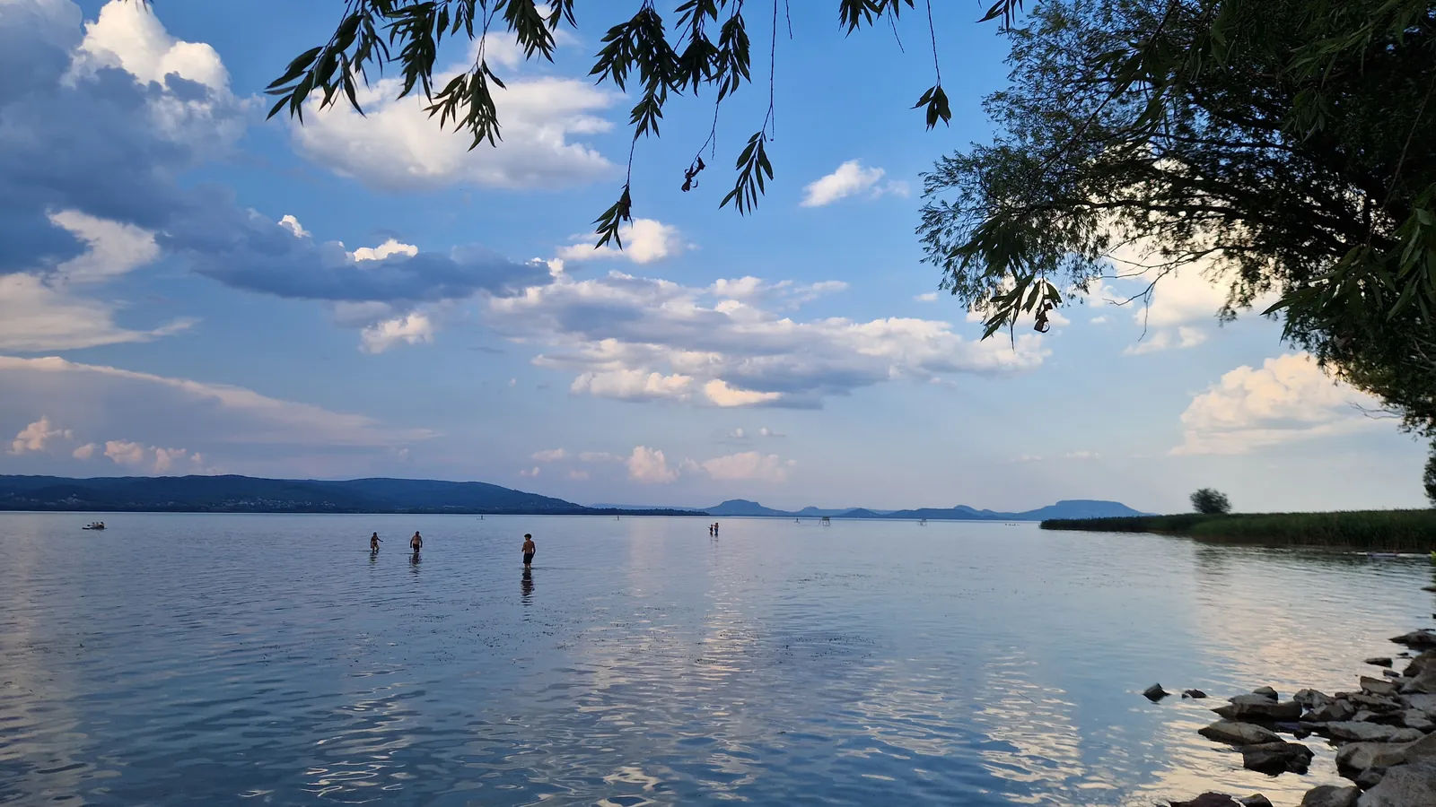 Badende stehen weit draußen im flachen Wasser des Balaton