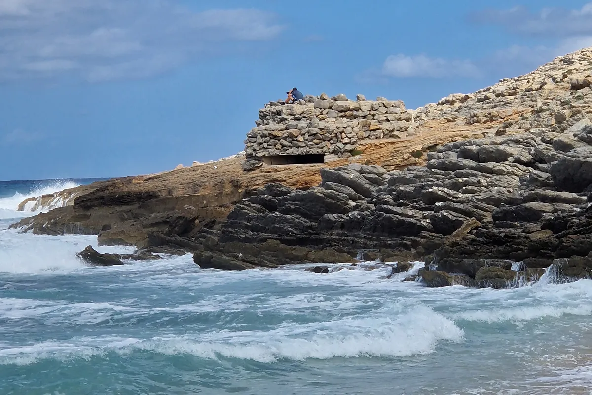 Hohe Wellen brechen an den Felsen der Cala Mesquida bei Wind im September