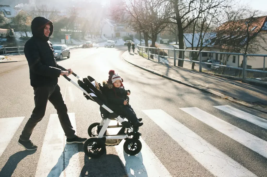 Vater mit Kind im Kinderwagen überqueren die Straße
