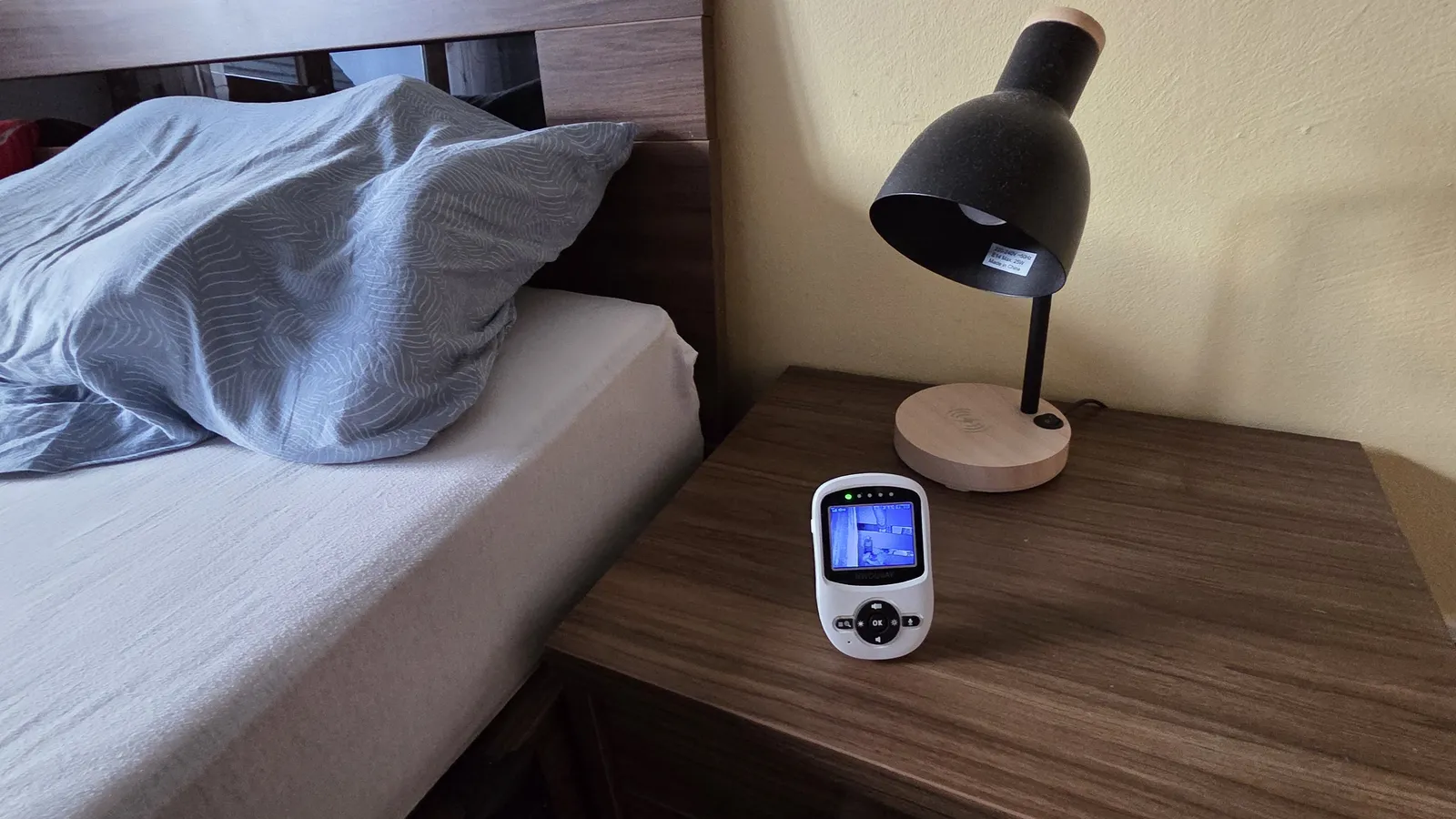 Elterneinheit unseres Babyphones mit Kamera auf dem Nachttisch neben dem Bett, auf dem Display das Bild aus dem Kinderzimmer