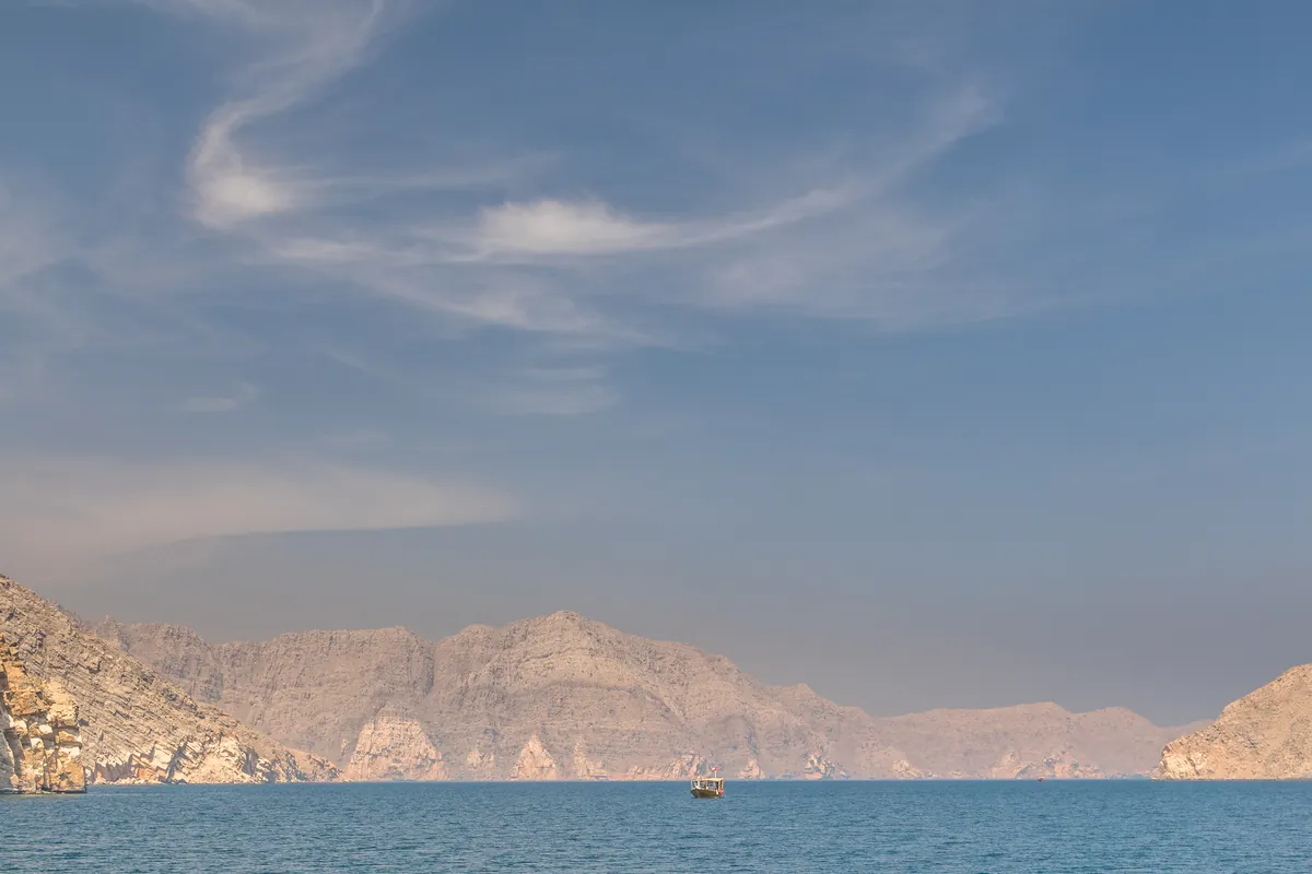 Fjord in Musandam mit hellen Felswänden und einem kleinen Boot auf ruhigem Wasser